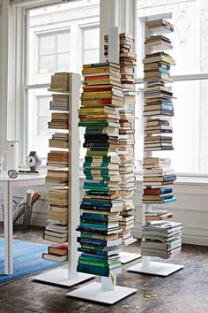 a tall stack of books sitting next to a window