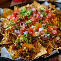 nachos with meat, cheese and onions in a black pan on a table