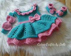 a crocheted dress and booties are on a fur rug