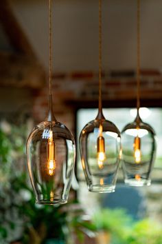 three glass hanging lights with one light turned on and the other turned off, in front of a window