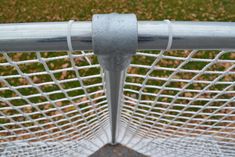 a close up view of the top of a tennis net with grass in the background