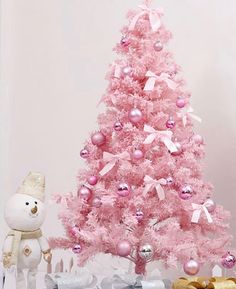 a pink christmas tree next to presents and a teddy bear on a shelf in front of it