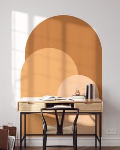 a desk and chair in front of a wall with an orange circle design on it