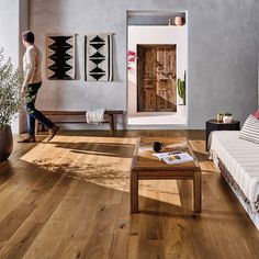 a man walking through a living room with wood floors