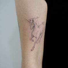 a woman's arm with a small tattoo of a unicorn on the left side