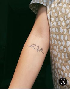 a woman's arm with a small bird tattoo on the left side of her arm