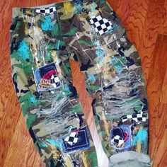 a pair of camouflage pants with patches and checkers on them, sitting on a wooden floor