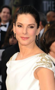 a woman in a white dress posing for the camera at an oscars awards event