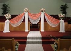 an aisle decorated with pink and white flowers in front of pews at a church