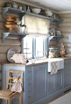 a kitchen with blue cabinets and shelves filled with dishes