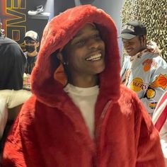 a man in a red furry jacket is smiling