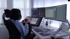 a person sitting at a computer desk with a glass of wine