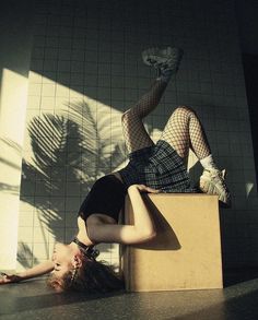 a woman laying on top of a box next to a tiled wall with her legs up