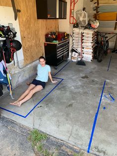 a woman sitting on the ground in front of a garage