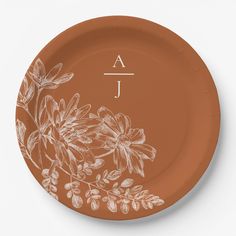 a brown plate with white flowers and the letter j on it's front side