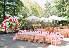 an outdoor table set up with red and white decorations