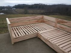 a wooden bed frame sitting on top of a cement floor next to a field with trees