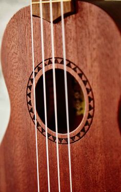 a close up of a wooden guitar with strings and fret holes in the middle