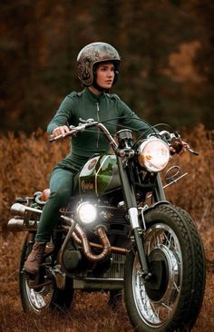 a man riding on the back of a motorcycle down a dirt road next to tall grass