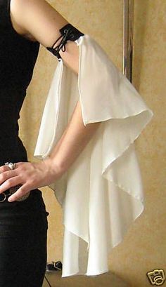 a woman in a black dress with a white jacket over her shoulders and hands on her hips