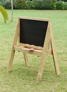 a wooden easel sitting on top of a grass covered field