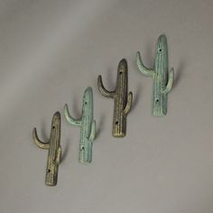 three metal cactus hooks on a white surface