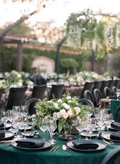 the table is set with black and white plates, silverware, and green linens