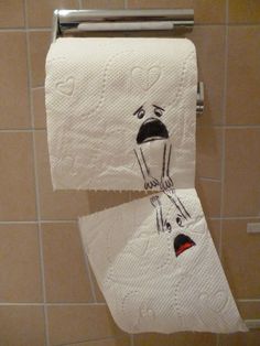 two white towels with faces drawn on them hanging from a towel rack in a bathroom