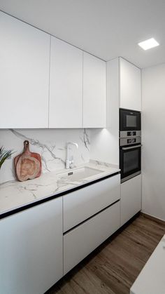 a kitchen with white cabinets and marble counter tops is pictured in this image, there is a black stove top on the wall