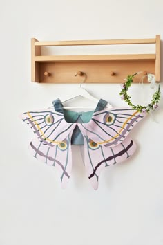 a paper butterfly is hanging on the wall next to a coat rack with a flower