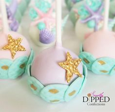 cake pops decorated with gold stars and mermaid themed icing are sitting on a table