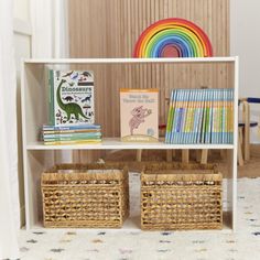 the bookshelf is filled with children's books and wicker bins