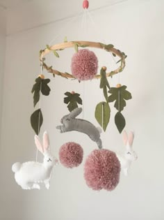 a baby mobile with two stuffed animals hanging from it's sides and some pink pom - poms on the other side