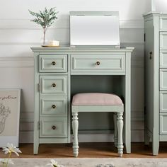 a green vanity with a mirror and stool in a white room next to a flower vase