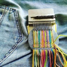 a pair of scissors sitting on the back of a jean jacket with multicolored thread