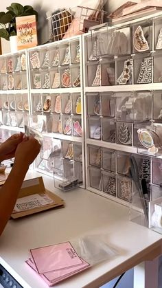 a woman sitting at a desk with lots of crafting supplies on the wall behind her