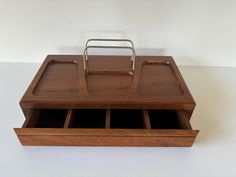 a wooden desk with two compartments and a metal holder on top of it, sitting on a white surface