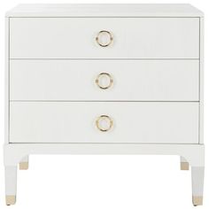 a white dresser with two drawers and gold handles on the bottom, against a white background