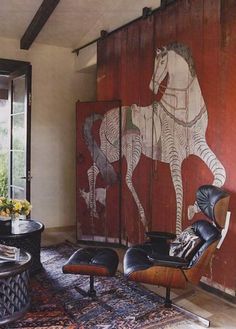 a living room with a horse painting on the wall and leather chairs in front of it