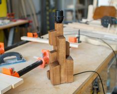 a wooden block sculpture sitting on top of a table next to a pair of pliers