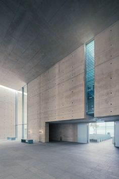 an empty room with concrete walls and windows on the wall is lit up by daylight