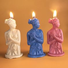 three small candles sitting next to each other in the shape of women's heads