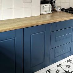 a kitchen counter with blue cabinets and white tiles on the floor, along with a toaster oven