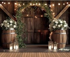 an outdoor wedding setup with candles and flowers on the floor, surrounded by barrels that have lights strung from them