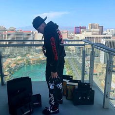 a man standing on top of a balcony next to suitcases and bags in front of him