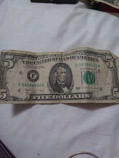 an old one dollar bill laying on top of a white sheet with other items around it