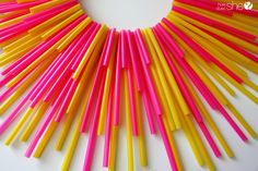 yellow and pink straws are arranged in the shape of a circle on a white surface