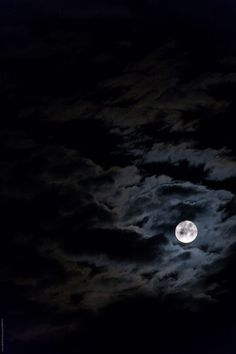 the full moon is shining brightly in the night sky with clouds and dark blue skies