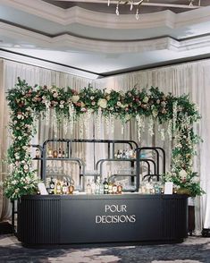 a bar with flowers and greenery on the front, along with candles in vases