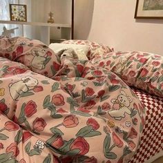 an unmade bed with pink and red flowers on it